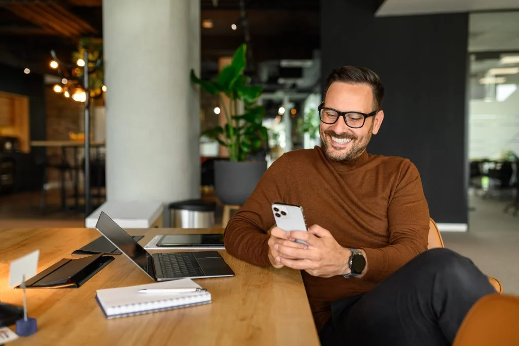 man in an office smiling looking at his phone