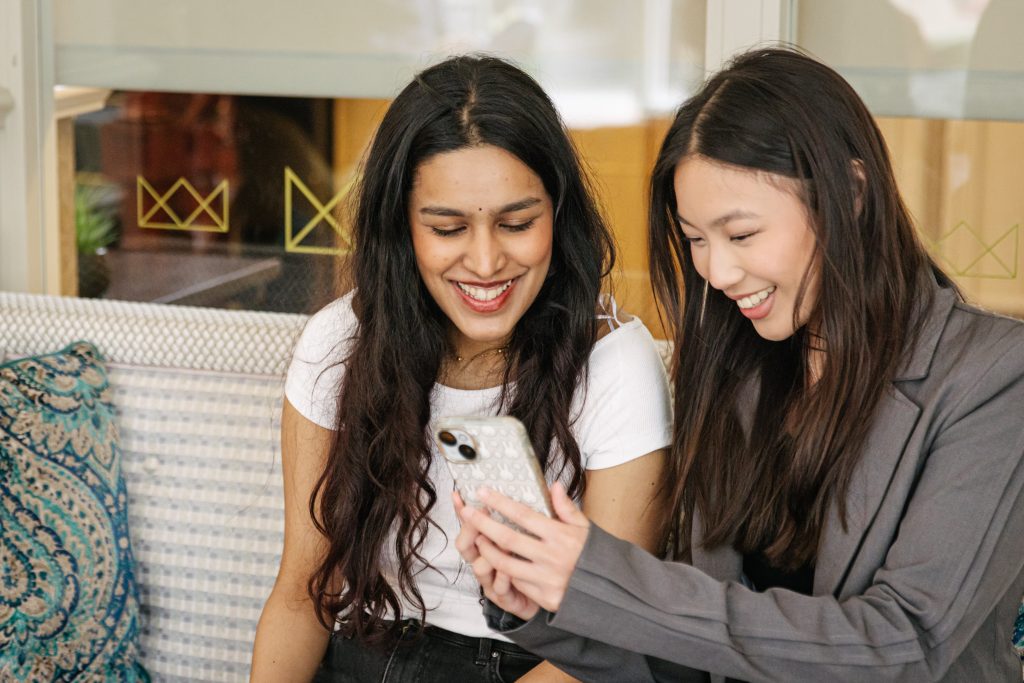 two woman looking to a phone and smiling