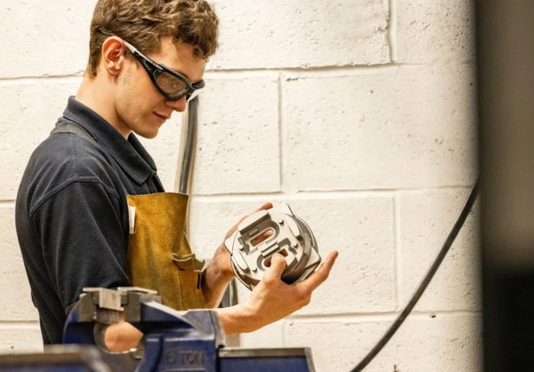 man looking into a pice of metal with glasses